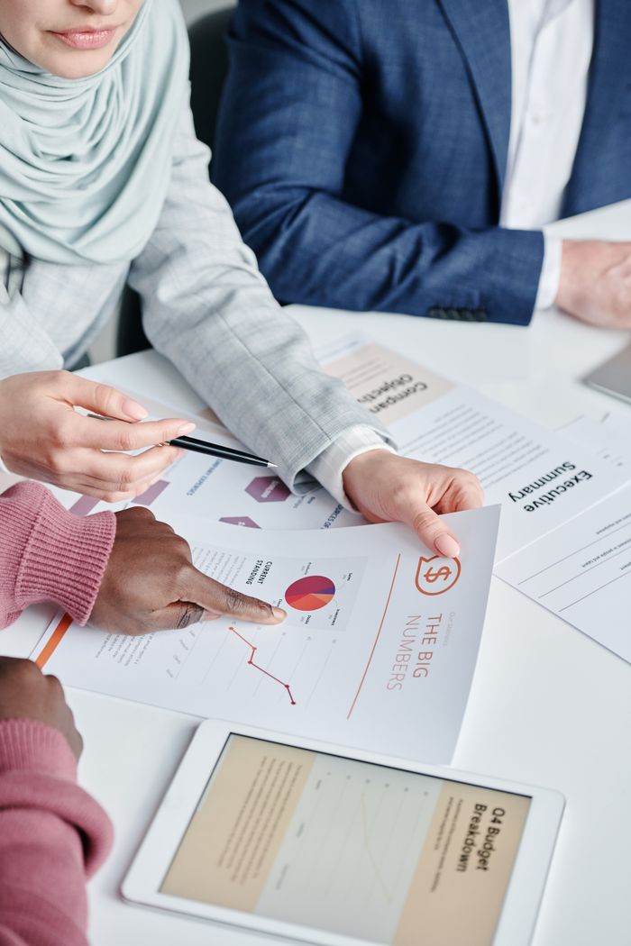 Diverse team members collaboratively reviewing business charts and documents during a meeting indoors.